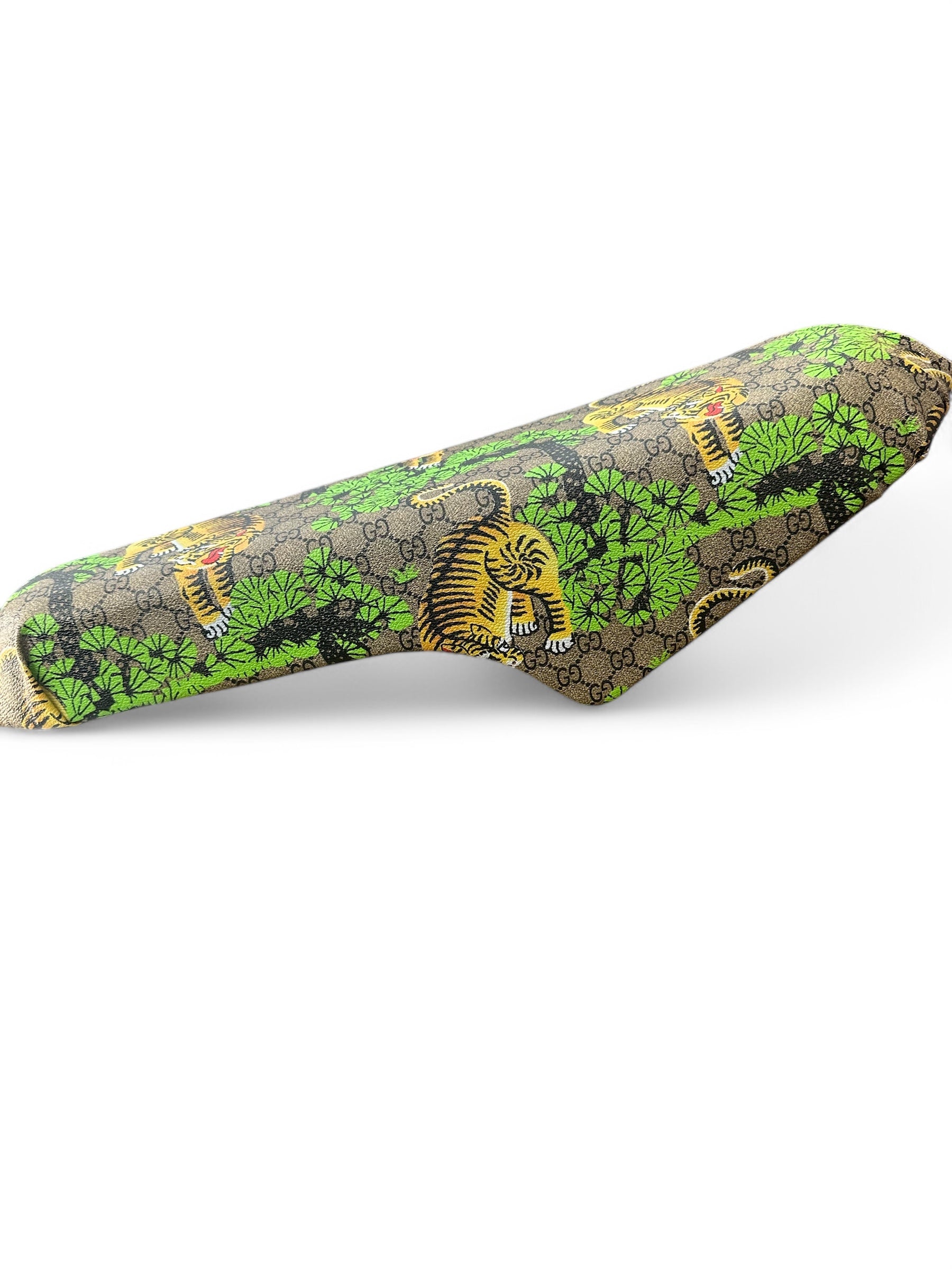 Een stof met een patroon van groen gebladerte, gele tijgers en een in elkaar verweven GG-logo is gedrapeerd over een QMWHEEL, OUXI FATBIKE ZADEL CUSTOM V20 - V8 - H9 in verschillende kleuren, tegen een witte achtergrond.
