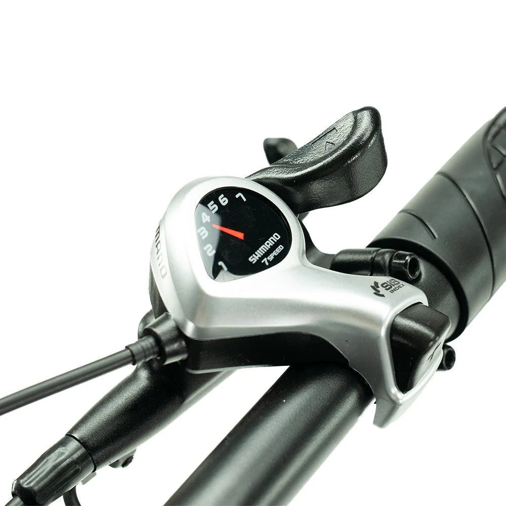 Close-up van een Shimano-versnellingshendel met 7 versnellingen, gemonteerd op het stuur van de OUXI FATBIKE V8 PRO (C80 PRO) – MODEL 2026, met de genummerde versnellingsindicator en een grip met structuur.