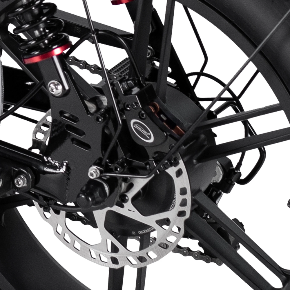 Close-up van het achterwiel van de 7GO FATBIKE - RSE SPECIAL EDITION - MODEL 2026 - ALARM, met de schijfremrotor, remklauw, spaken, veer en een deel van het zwarte frame. De afbeelding toont de belangrijkste mechanische en structurele onderdelen die zijn ontworpen voor krachtige ondersteuning op deze elektrische fatbike van 7GO.
