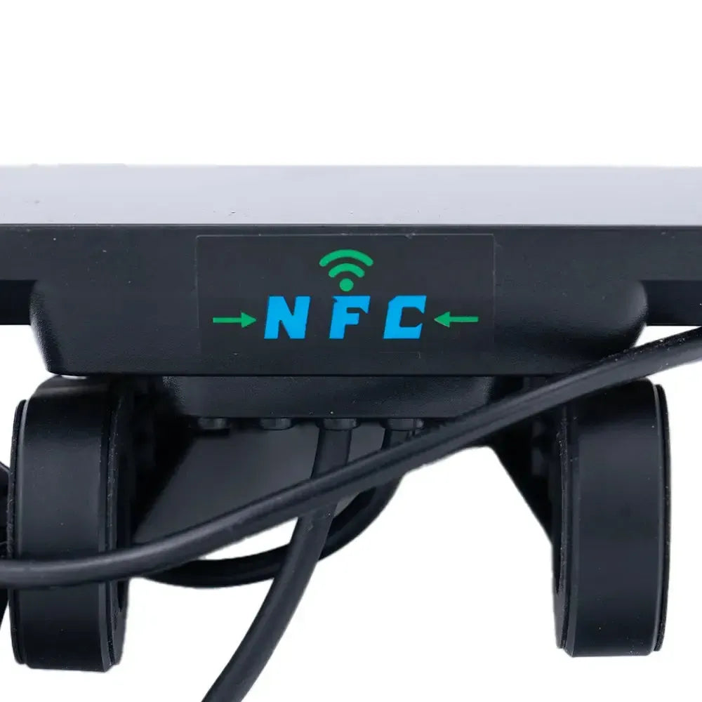 Close-up van een QMWHEEL FATBIKE S20 (PRO) - NFC - DISPLAY met een label waarop het NFC-symbool en tekst staan, evenals pijlen die naar links en rechts wijzen. Onder het label zijn kabels zichtbaar, en het apparaat – dat lijkt op de modellen die worden gebruikt voor het S20 fatbike-display of de V20-modellen – lijkt voorzien te zijn van wieltjes of rollen.