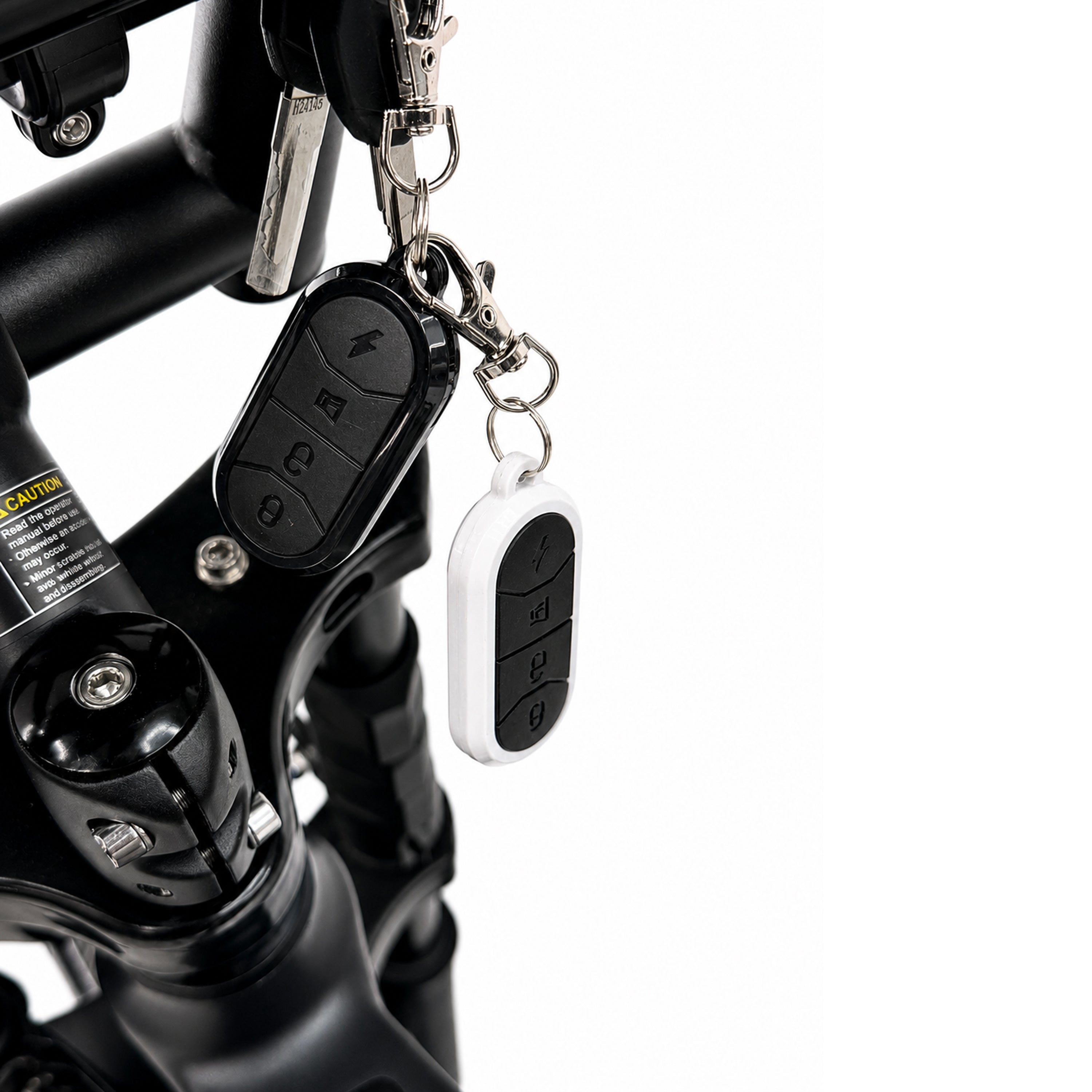 Een close-up van twee afstandsbedieningen met sleutelhangers die aan het stuur van de OUXI FATBIKE GT24 – MODEL 2026 zijn bevestigd; de sleutel zit in het contactslot en de fiets is uitgerust met hydraulische remmen en een alarmsysteem.