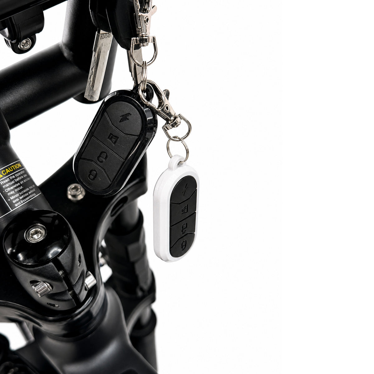 Een close-up van twee afstandsbedieningen met sleutelhangers die aan het stuur van de OUXI FATBIKE GT24 – MODEL 2026 zijn bevestigd; de sleutel zit in het contactslot en de fiets is uitgerust met hydraulische remmen en een alarmsysteem.