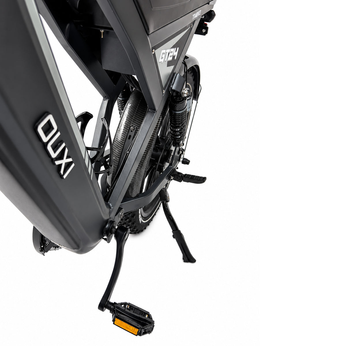 Close-up van de zwarte FATBIKE OUXI GT24 – MODEL 2026 van OUXI, gezien vanaf de linkerkant, waarbij het pedaal, de standaard, de vering en een deel van het fietsframe op een witte achtergrond worden uitgelicht.