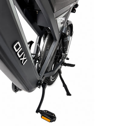 Close-up van de zwarte FATBIKE OUXI GT24 – MODEL 2026 van OUXI, gezien vanaf de linkerkant, waarbij het pedaal, de standaard, de vering en een deel van het fietsframe op een witte achtergrond worden uitgelicht.