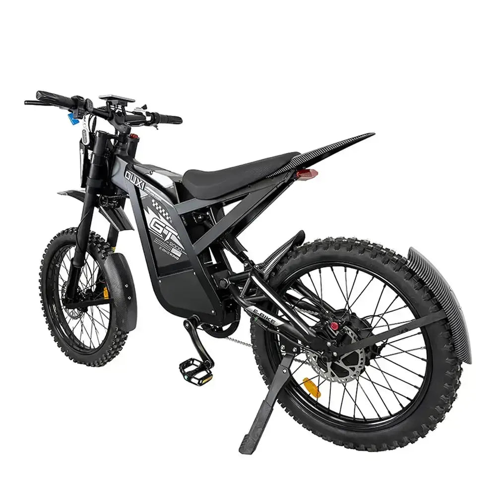Een zwarte OUXI FATBIKE GT2000 CROSS – OFFROADFIETS (model 2026) met dikke banden, een robuust frame, hydraulische remmen, spatborden voor en achter, pedalen, een standaard en opvallende GT-afbeeldingen op de zijkant wordt vanuit een hoek van achteren afgebeeld tegen een witte achtergrond. Dit hoogwaardige OUXI-model is bovendien voorzien van een geïntegreerd alarmsysteem en zorgt voor een opwindende rijervaring dankzij de krachtige motor van 2000 W.