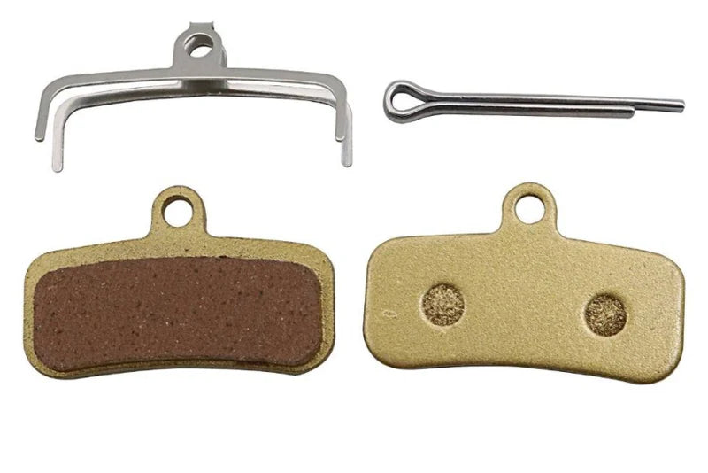 Twee originele OUXI GT2000 hydraulische schijfremblokken (REMBLOKKEN - OUXI GT2000 - ORIGINEEL) met een bruin wrijvingsoppervlak, een metalen veerklem en een borgpen worden getoond op een witte achtergrond – ideaal voor je e-bike of OUXI-fiets.