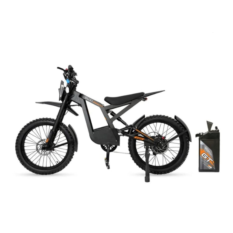 Een zwarte elektrische crossmotor met dikke banden, voorzien van een zijstandaard en geïnspireerd op het ontwerp van een fatbike, wordt in profiel getoond. Naast de motor staat rechtop een afneembare e-bike-accu met het opschrift „OUXI ACCU - BATTERIJ - GT2000 - ORIGINEEL”.