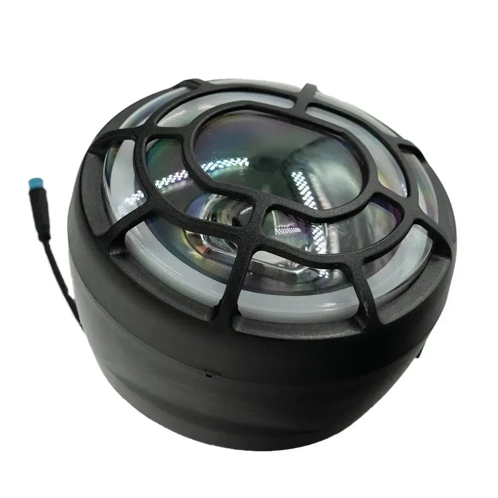 The QMWHEEL - FATBIKE V20 - KOPLAMP - ORIGINEEL is a round black LED headlight for fatbikes, equipped with a protective grille and attached wiring. Showcasing advanced lighting technology, the headlight is displayed from an angled perspective against a white background.