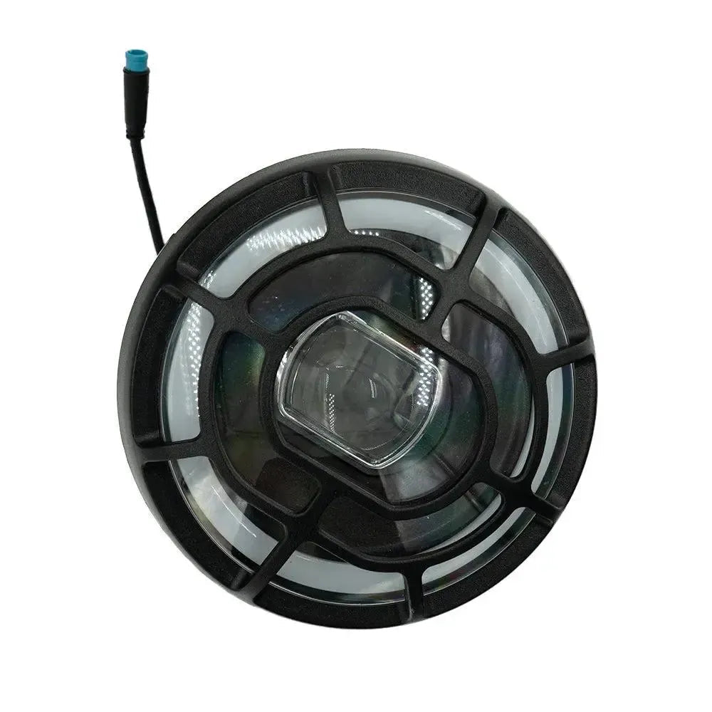 The QMWHEEL FATBIKE V20 Koplamp – Origineel is a round, black LED headlight with a clear lens, encircled by a white halo ring and accented with a distinctive black grid pattern. Featuring advanced verlichtingstechnologie inspired by V20 modellen, it includes a short black cable with a blue connector extending from the side—reflecting the premium design of Fatbike koplampen. The headlight is shown from an overhead perspective.