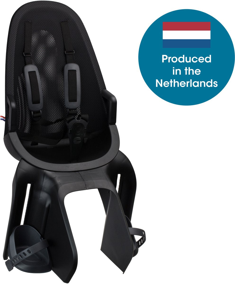 A black Qibbel Air ACHTERZITJE - Q900 kinderfiets achterzitje with harness and foot straps is displayed next to a blue circle featuring the Dutch flag and the words “Produced in the Netherlands.” This lightweight achterzitje blends safety with renowned Dutch quality craftsmanship.