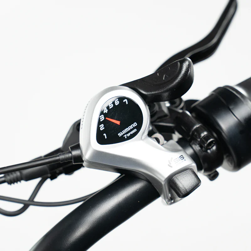 Close-up van een Shimano-versnellingshendel met 7 versnellingen en een remhendel, gemonteerd op het stuur van de OUXI FATBIKE V8 (C80) – MODEL 2026, met zichtbare kabels en hydraulische remmen, afgebeeld tegen een strakke witte achtergrond.