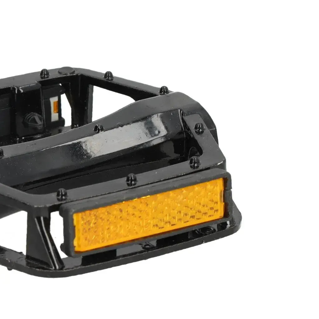 Close-up van een zwart OUXI - QMWHEEL - 7GO - TRAPPERS-pedaal met een oranje reflectorplaat. Het rechthoekige pedaal heeft zichtbare bouten en een gestructureerd reflectorpaneel, wat de zichtbaarheid en veiligheid verhoogt – ideaal als vervangingspedalen voor fatbikes of voor gebruik met QMWHEEL-, OUXI- of 7GO-fatbikes.