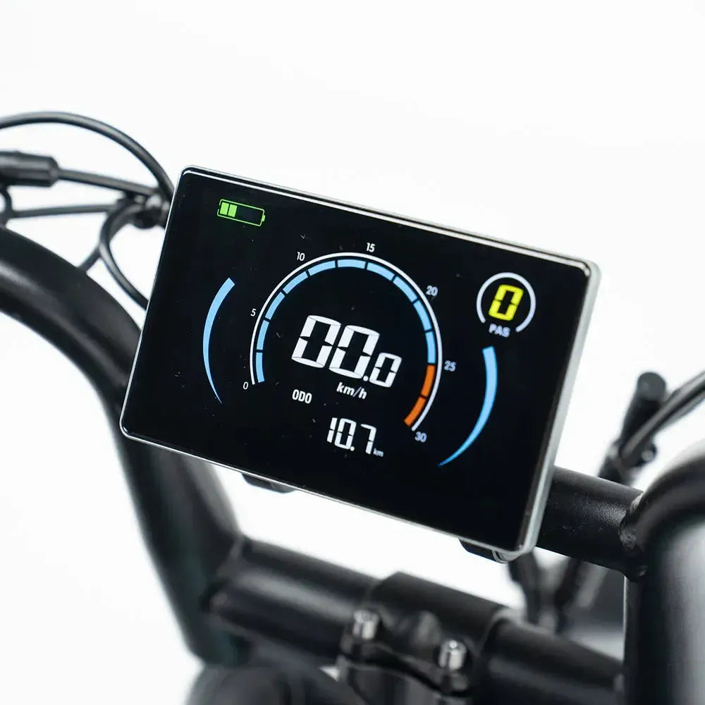 Close-up van een digitaal display op het stuur van de FATBIKE OUXI C80 MINI - BLAUW – MODEL 2026, waarop de snelheid, het batterijniveau, de instelling voor trapondersteuning en de kilometerteller te zien zijn tegen een zwart-witte achtergrond. Deze compacte elektrische fatbike van OUXI is voorzien van geavanceerde technologie – waaronder hydraulische remmen en een ingebouwd alarm – gecombineerd met een strak ontwerp voor een moeiteloze rit.